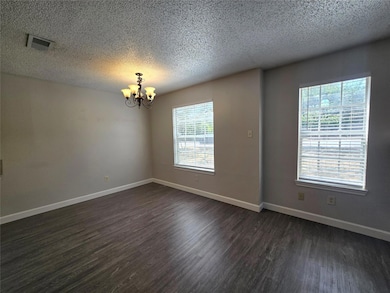 Spare room with a textured ceiling, dark wood-sty