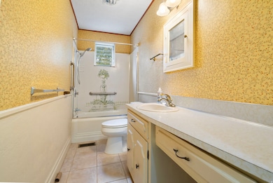 Bathroom with vanity, shower / bathtub combination, light tile patterned floors, and wallpapered walls