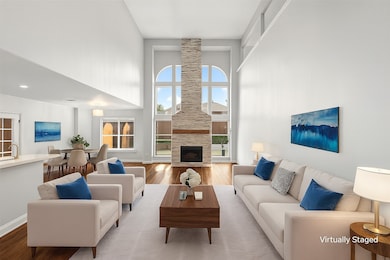 Living room featuring wood finished floors, a high ceiling, and a large fireplace