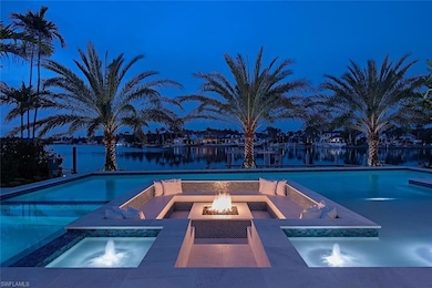 Pool featuring a water view, an in ground hot tub, and an outdoor fire pit