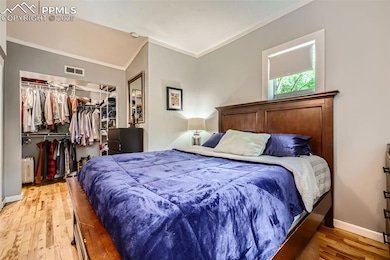 Bedroom with ornamental molding, light wood-style floors, a closet, a walk in closet, and baseboards