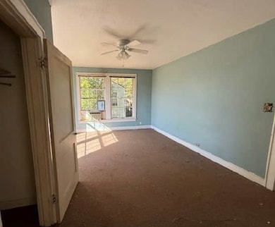Unfurnished room with a ceiling fan and dark colored carpet
