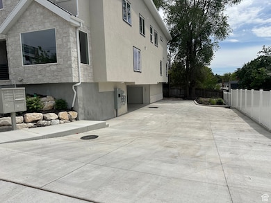View of property exterior with mail area, stone siding, stucco siding, and an attached garage