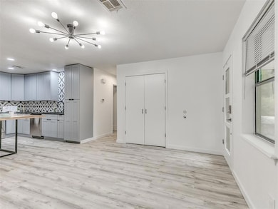 Kitchen featuring gray cabinetry, a chandelier, li