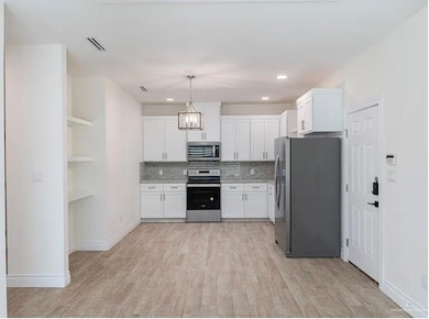 Kitchen featuring light wood finished floors, white cabinets, tasteful backsplash, visible vents, and appliances with stainless steel finishes