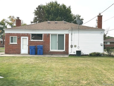 Back of house with a chimney, a yard, a patio, and a shingled roof