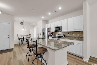 Kitchen with white cabinetry, appliances with stai