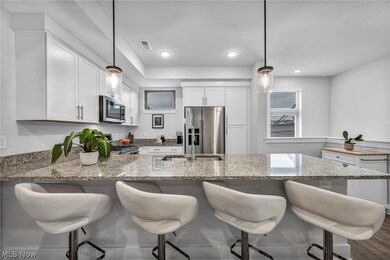 Kitchen featuring kitchen peninsula, hanging light fixtures, light stone countertops, and appliances with stainless steel finishes