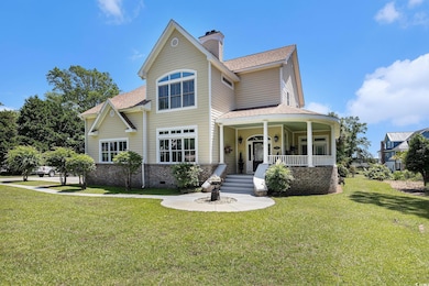 View of front facade featuring covered porch, a front lawn, roof with shingles, a chimney, and brick siding