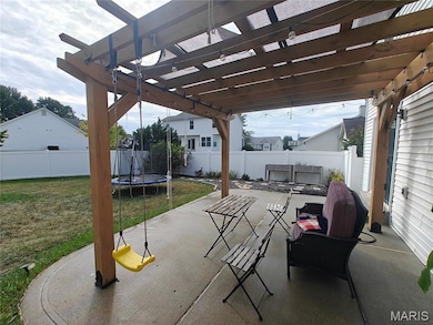 Fenced backyard featuring a trampoline, a patio area, and a pergola