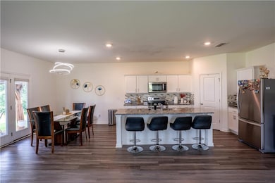 Kitchen featuring stainless steel appliances, decorative backsplash, light stone countertops, recessed lighting, and a kitchen bar