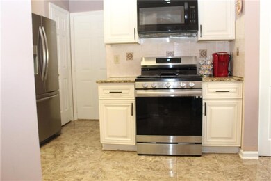 Kitchen with stainless steel appliances, backsplash, and light stone counters