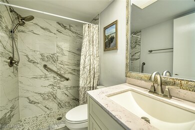 Bathroom with toilet, vanity, and a stall shower