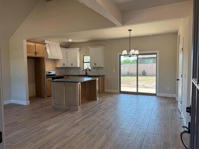 Kitchen featuring range hood, dark countertops, a chandelier, and wood finished floors