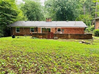 Back of property with fence, a chimney, a forest v
