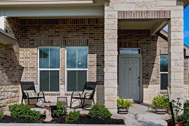 Property entrance featuring brick siding, a porch, and stone siding
