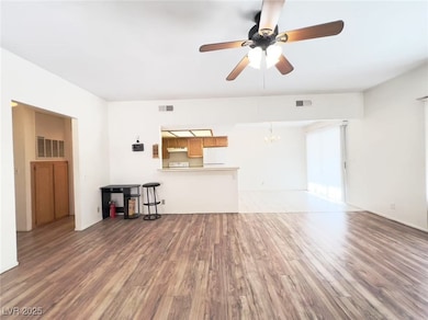 Unfurnished living room with dark wood finished floors, a ceiling fan, and a chandelier
