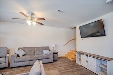 Living area featuring wood finished floors, stairs, and ceiling fan