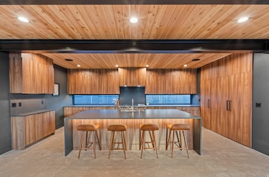 Kitchen featuring modern cabinets, a breakfast bar area, brown cabinetry, a spacious island, and backsplash