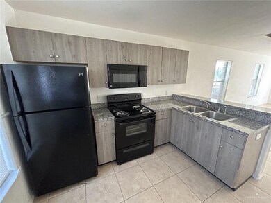 Kitchen with black appliances, light tile patterned floors, gray cabinets, dark countertops, and a peninsula