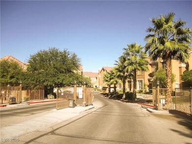 View of asphalt road with curbs, a gate, and a gated entry