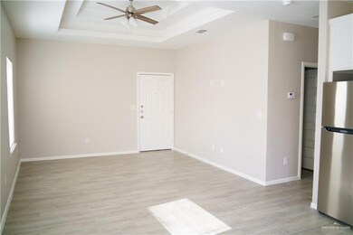 Empty room featuring ceiling fan, a raised ceiling, light wood-style floors, and baseboards