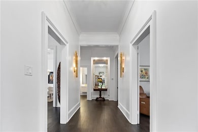 Hallway with ornamental molding, dark wood-type flooring, and baseboards