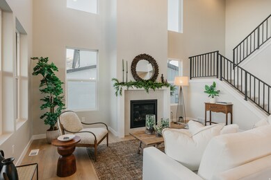 Living area featuring wood finished floors, a fireplace, a towering ceiling, and stairway