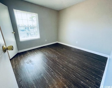 Spare room with dark wood finished floors and base