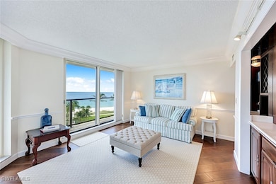 Living room featuring a textured ceiling, a water view, dark wood-style floors, and crown molding