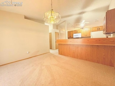 Kitchen with decorative light fixtures, light carpet, a chandelier, white appliances, and a textured ceiling