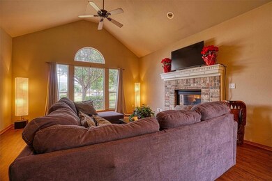 Living room with wood finished floors, high vaulted ceiling, ceiling fan, and a fireplace