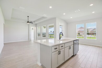Kitchen featuring white cabinetry, a tray ceiling, recessed lighting, a kitchen island with sink, and light wood-type flooring