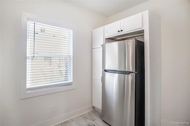 Kitchen featuring freestanding refrigerator and white cabinets