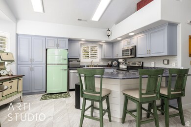 Kitchen featuring stainless steel appliances, dark countertops, a peninsula, and gray cabinetry