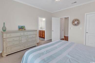 Carpeted bedroom featuring ensuite bathroom, ornam