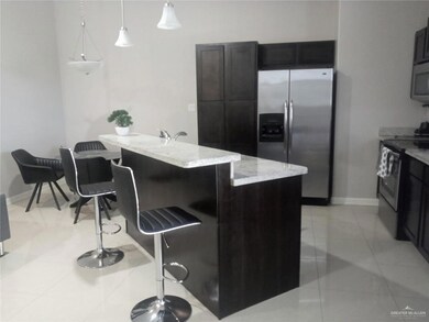 Kitchen featuring appliances with stainless steel finishes, light stone counters, an island with sink, a breakfast bar area, and light tile patterned flooring