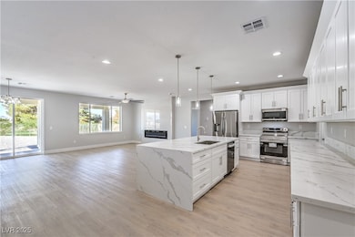 Kitchen featuring ceiling fan, open floor plan, white cabinets, light stone counters, and recessed lighting