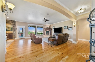 Living area with a lit fireplace, light wood finished floors, a ceiling fan, arched walkways, and a textured ceiling