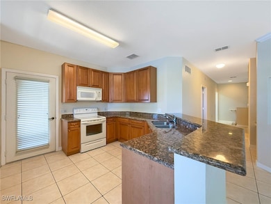 Kitchen with white appliances, a peninsula, light
