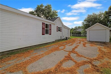 View of side of property featuring a detached garage, an outdoor structure, and driveway