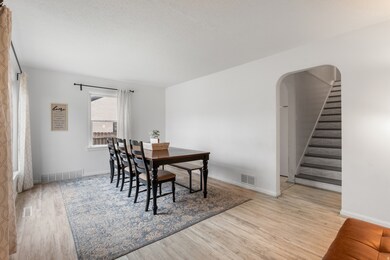 Dining area with light wood-style floors, arched walkways, a textured ceiling, and stairs