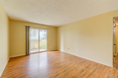 Unfurnished room with a textured ceiling and light wood-type flooring