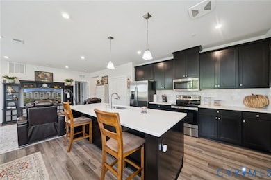 Kitchen featuring open floor plan, appliances with stainless steel finishes, tasteful backsplash, hanging light fixtures, and a breakfast bar