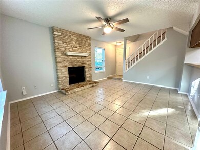 Unfurnished living room with light tile patterned floors, a textured ceiling, ceiling fan, a fireplace, and stairs