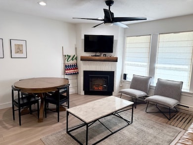 Living area with a fireplace, light LVP floors, a ceiling fan, recessed lighting, and a baseboard radiator