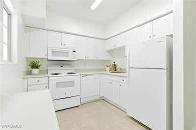 Kitchen featuring white appliances, light countert