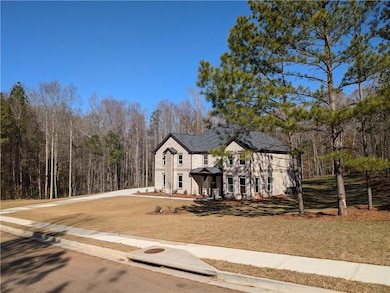 View of front of house with driveway and a forest 