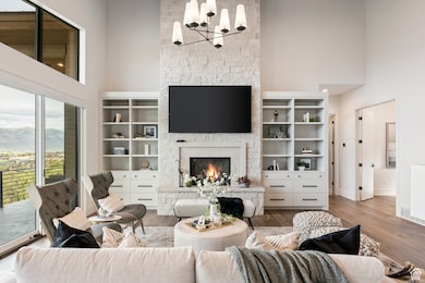 Living area with a high ceiling, a stone fireplace, wood finished floors, and a chandelier