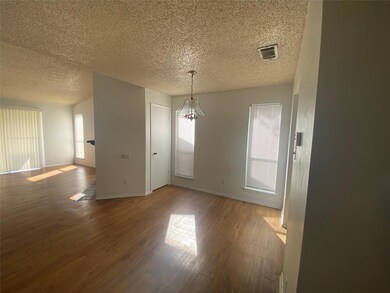 Unfurnished dining area featuring a chandelier, wood finished floors, and a textured ceiling